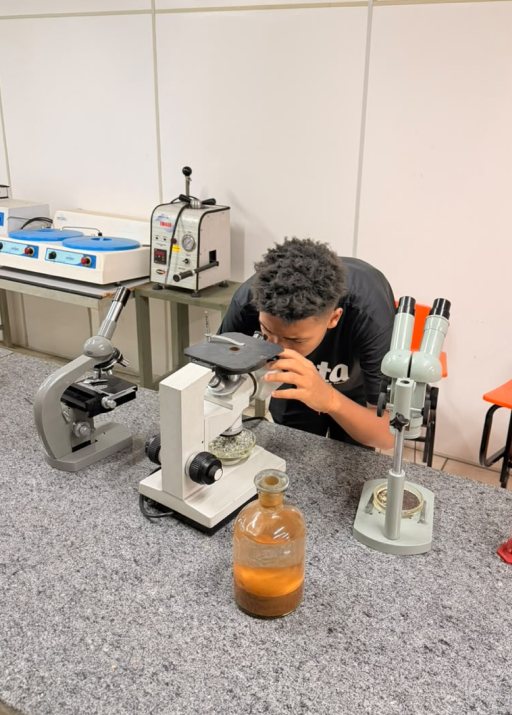 Aluno usando microscópio no laboratório de mineração